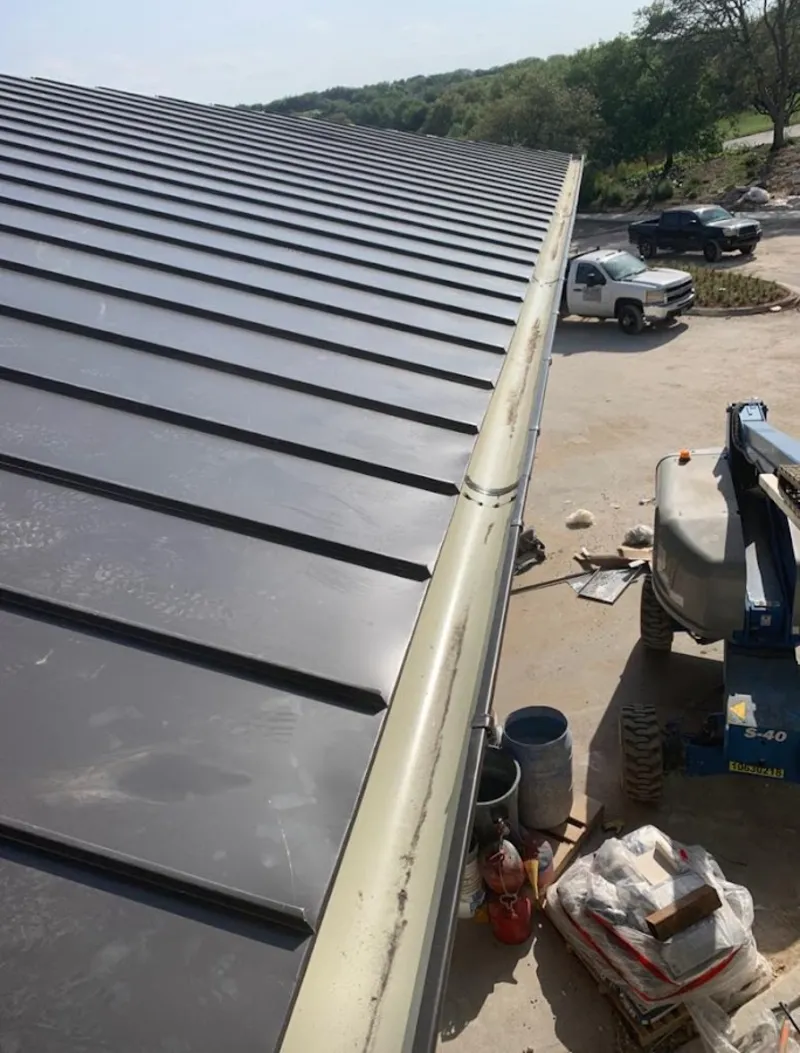 Standing seam panel and gutter detail on a metal roofing jobsite in Sayre